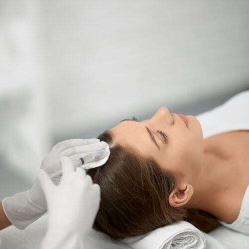 Beautician in protective mask doing procedure for hair.